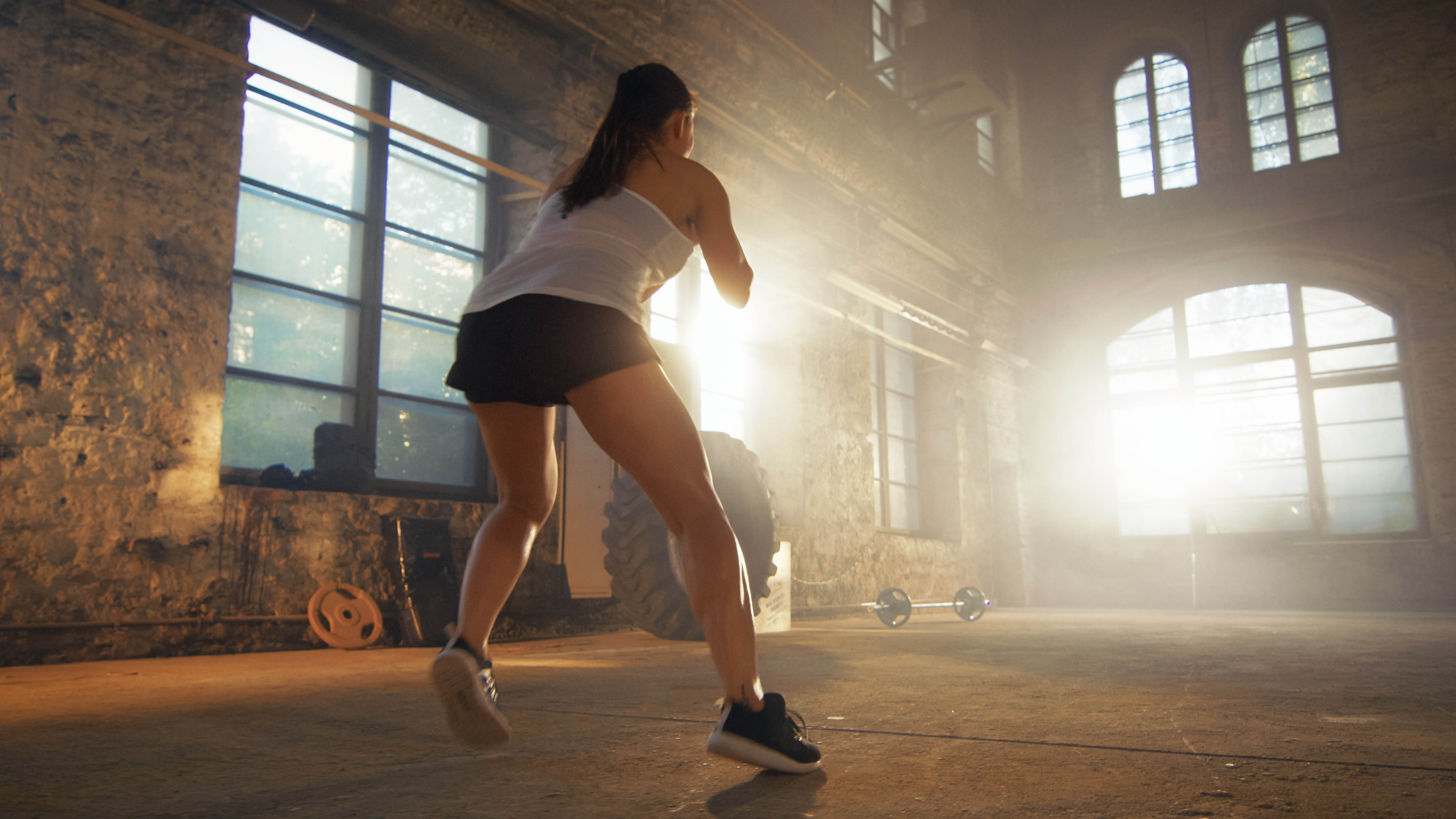 Young woman completing cardio intervals alone in a fitness studio, back is to the camera Young woman completing cardio intervals alone in a fitness studio, back is to the camera
